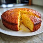 A slice of moist 1-bowl yellow birthday cake on a white plate, showing its tender crumb.