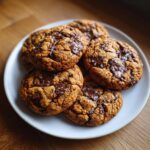 A plate of freshly baked Chocolate Chip Tahini Cookies, sprinkled with sea salt.