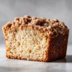 A close-up of a moist slice of Coffee Cake with a generous cinnamon crumble topping.