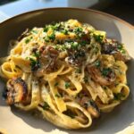 A close-up of a bowl of Creamy Mushroom Fettuccine, garnished with fresh parsley and grated cheese.