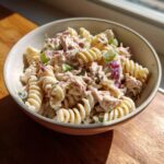 A bowl of Easy Tuna Pasta Salad made with rotini pasta, tuna, red onion, and celery in a creamy dressing.