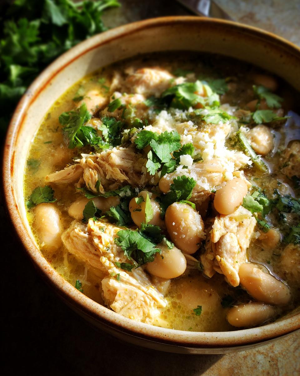 A close-up of a bowl of Easy White Chicken Chili, featuring shredded chicken, white beans, and cilantro.