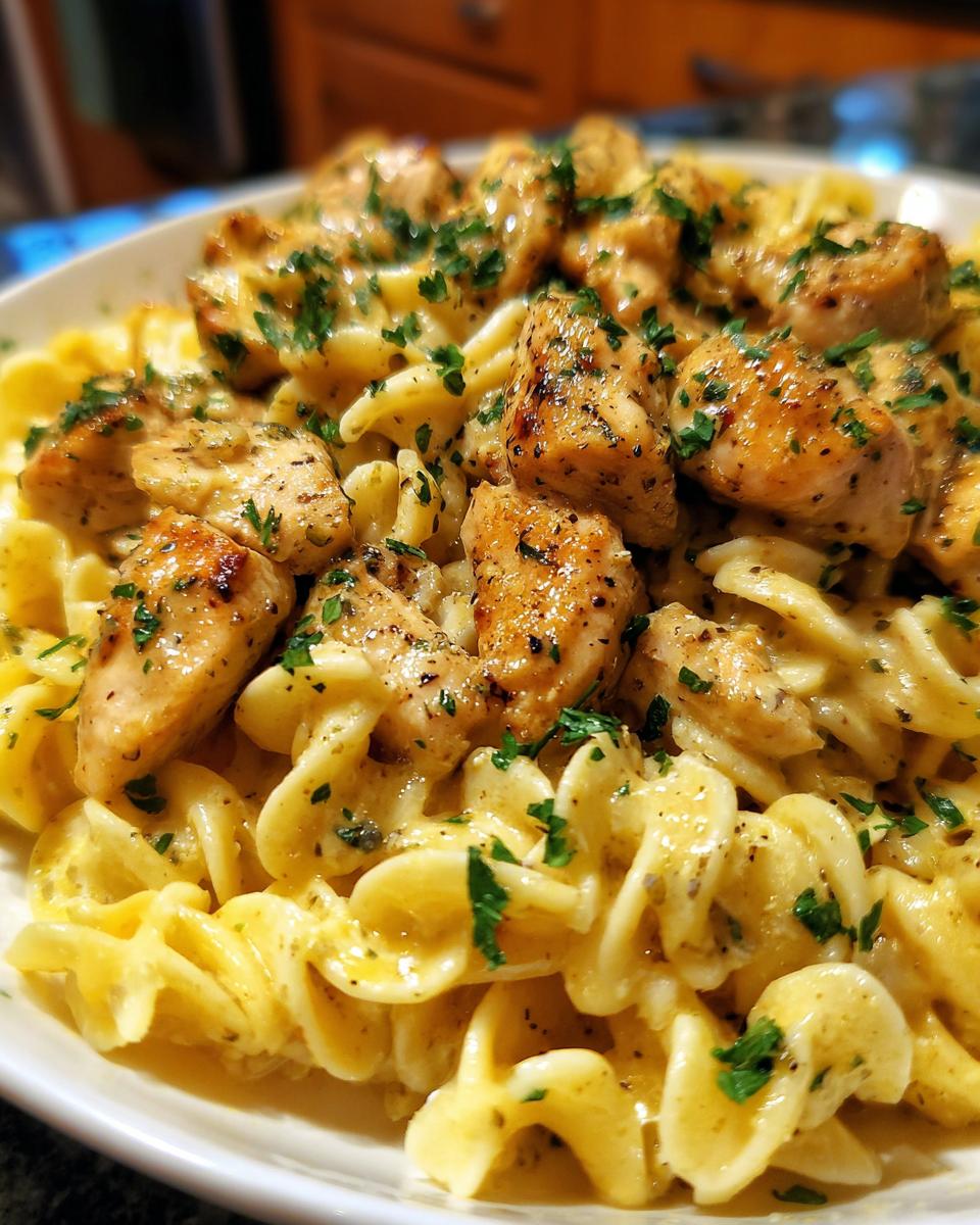 A close-up of delicious Garlic Butter Chicken Pasta topped with chopped parsley.