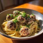 A close-up of a bowl of Garlic Butter Meatball Pasta, featuring spaghetti, meatballs, and fresh parsley.