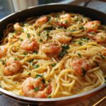 Close-up of delicious Garlic Butter Shrimp Pasta in a pan, garnished with parsley.