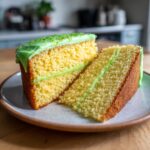 Two slices of Key Lime Cake on a plate, showing the fluffy yellow cake, green lime filling, and bright green frosting with sprinkles.