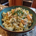 A close-up of creamy Lemon Dill Salmon Pasta topped with fresh dill and flaked salmon.