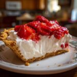 A delicious slice of No Bake Strawberry Cream Pie with a graham cracker crust, creamy filling, and fresh strawberries.