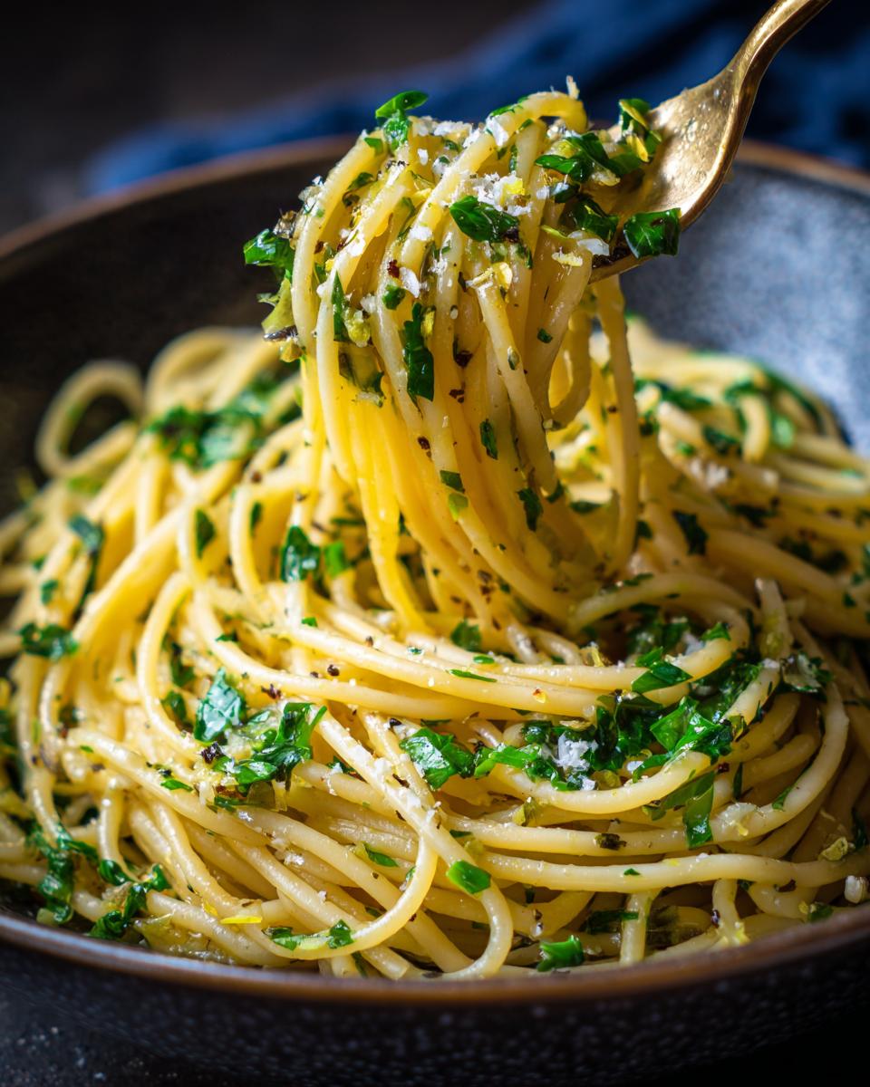 A fork lifting a swirl of Spaghetti Aglio e Olio, glistening with olive oil and flecked with parsley and garlic.