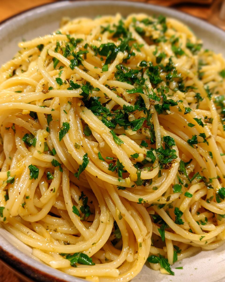 Close-up of a bowl of Spaghetti Aglio e Olio, tossed with garlic, olive oil, and fresh parsley.