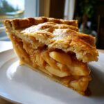 A close-up of a thick slice of homemade apple pie, showing flaky crust and rich filling, perfect for Fathers Day treat.