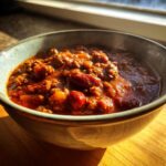 Close-up of a steaming bowl filled with rich, hearty Best Crockpot Chili featuring ground meat and kidney beans.