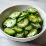 Close-up of thinly sliced cucumbers marinated in a clear dressing, showcasing the Best Cucumber Salad recipe.
