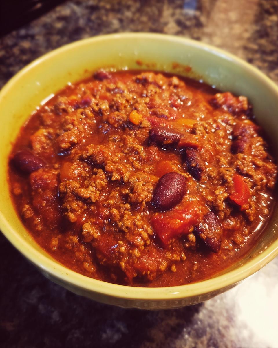 Close-up of a thick, rich bowl of Best Slow Cooker Chili featuring ground meat and kidney beans.