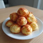 A stack of golden brown, baked Breakfast Pancake Poppers piled high on a white plate.
