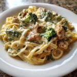 Close-up of creamy Chicken And Broccoli Alfredo pasta with fettuccine, chunks of seasoned chicken, and bright green broccoli florets.