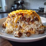A perfectly molded serving of Creamy Queso Rice With Steak, topped generously with melted white and shredded cheddar cheese.