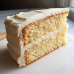 Close-up of a moist slice of vanilla cake with white frosting, perfect for a Twenty First Birthday Cake.