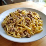 A white plate piled high with Garlic Parmesan Beef Pasta featuring fettuccine noodles and seasoned ground beef.