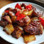 Close-up of glazed chicken pieces mixed with caramelized pineapple chunks and red peppers from the Hawaiian Chicken Sheet Pan dinner.
