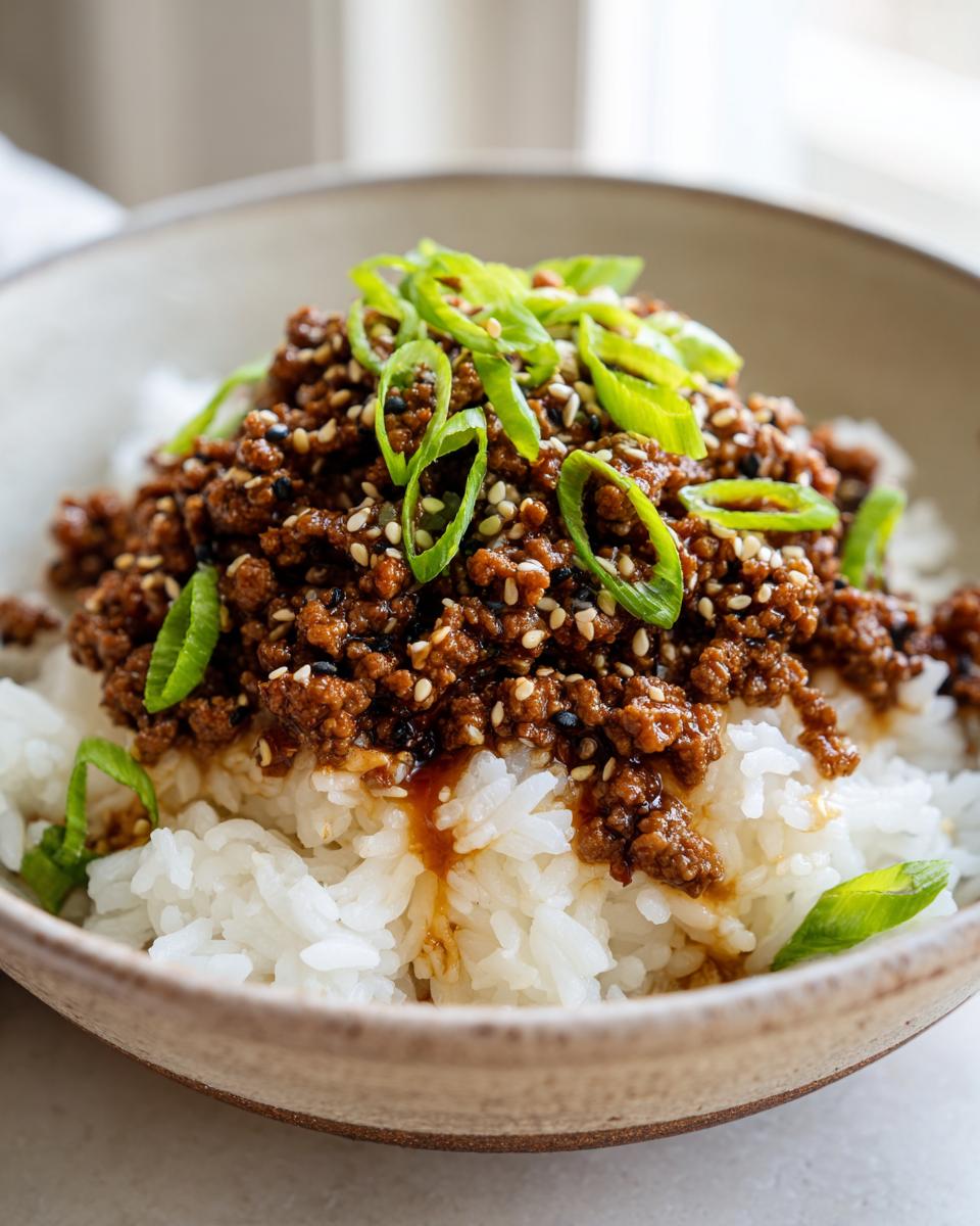 A close-up of a Korean Beef Bowl featuring savory ground beef served over white rice and topped with sesame seeds and sliced green onions.