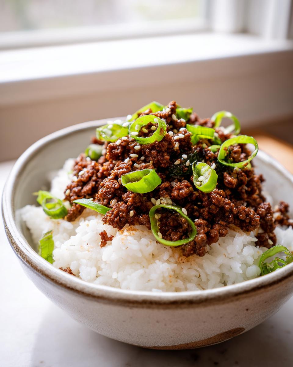Close-up of a Korean Beef Bowl featuring seasoned ground beef over white rice, topped with sliced green onions and sesame seeds.