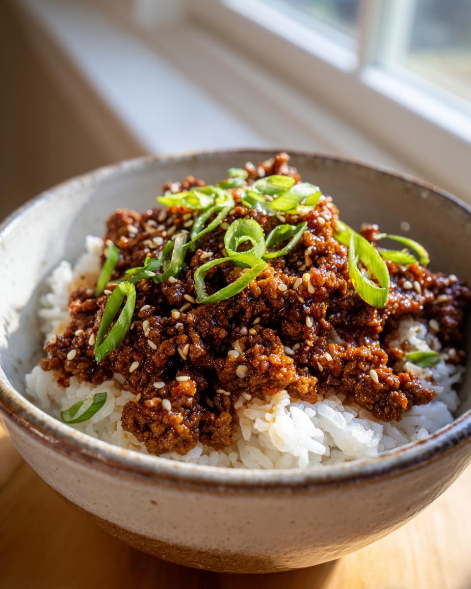 A close-up of a Korean Beef Bowl featuring savory ground beef over white rice, topped with green onions and sesame seeds.