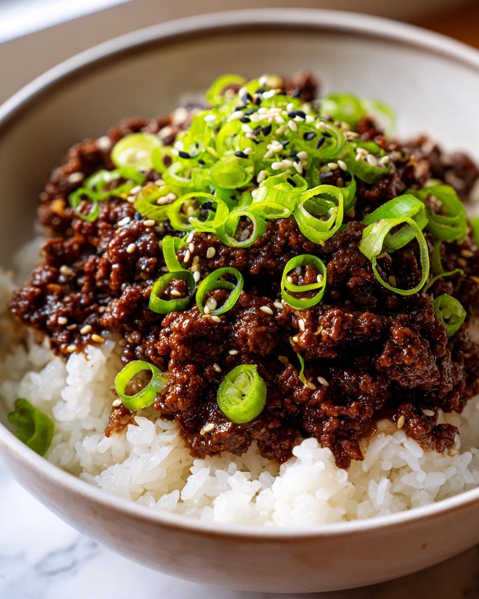 Close-up of a Korean Ground Beef Bowl featuring savory ground beef over white rice, topped with green onions and sesame seeds.