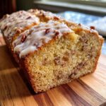 Close-up of a moist slice of Butter Pecan Cake topped with a sweet glaze and chopped pecans.