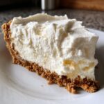 Close-up of a creamy slice of no-bake cheesecake with a thick graham cracker crust, perfect for Nineteen Summer Cheesecake Recipes.