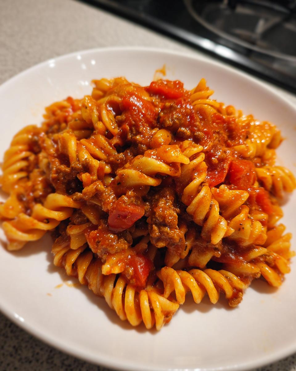 Close-up of rotini pasta coated in a rich, creamy tomato and ground beef sauce, part of the Quick And Easy Creamy Beef Pasta recipe.