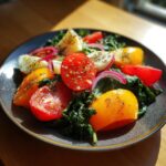 Close-up of a simple lunch idea: a colorful salad with kale, sliced red and yellow tomatoes, hard-boiled egg wedges, and red onion.