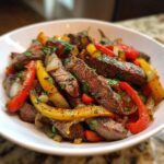 Close-up of sliced steak mixed with colorful bell peppers and onions, ready to serve for Sheet Pan Steak Fajitas.