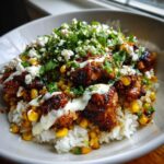 Close-up of a Street Corn Chicken Rice Bowl featuring seasoned chicken, corn, white rice, crema, cotija cheese, and fresh cilantro.