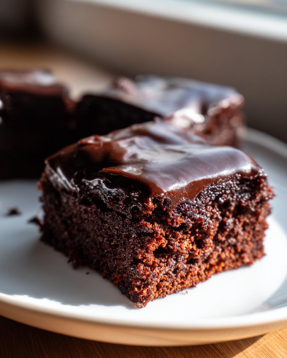 Close-up of a rich, dark chocolate slice of Texas Sheet Cake topped with glossy, melted chocolate frosting.