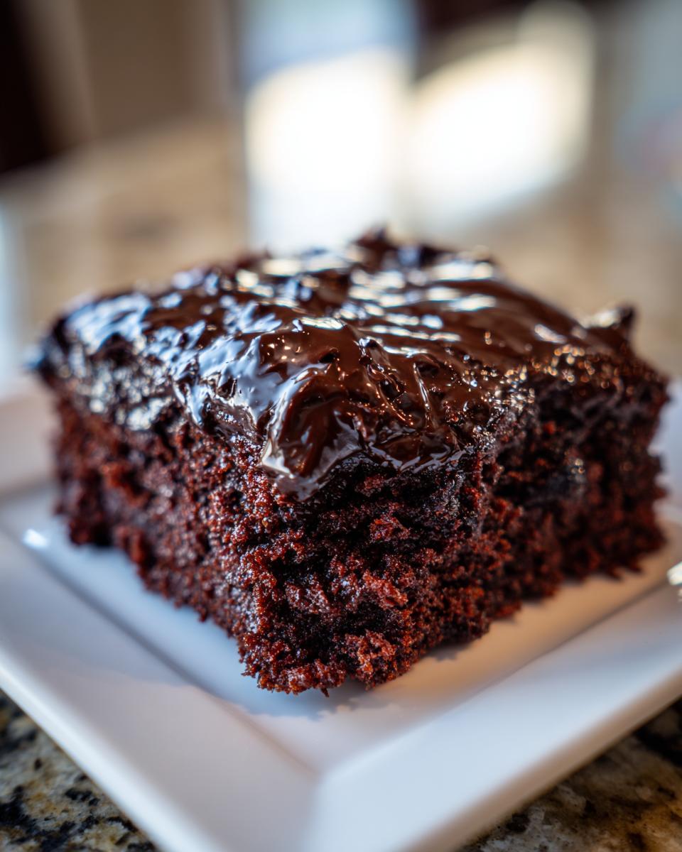 Close-up of a rich, dark chocolate slice of Texas Sheet Cake topped with glossy, melted chocolate frosting.
