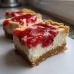 Close-up of a rich slice of Ultimate Strawberry Cheesecake Bars with a thick graham cracker crust.