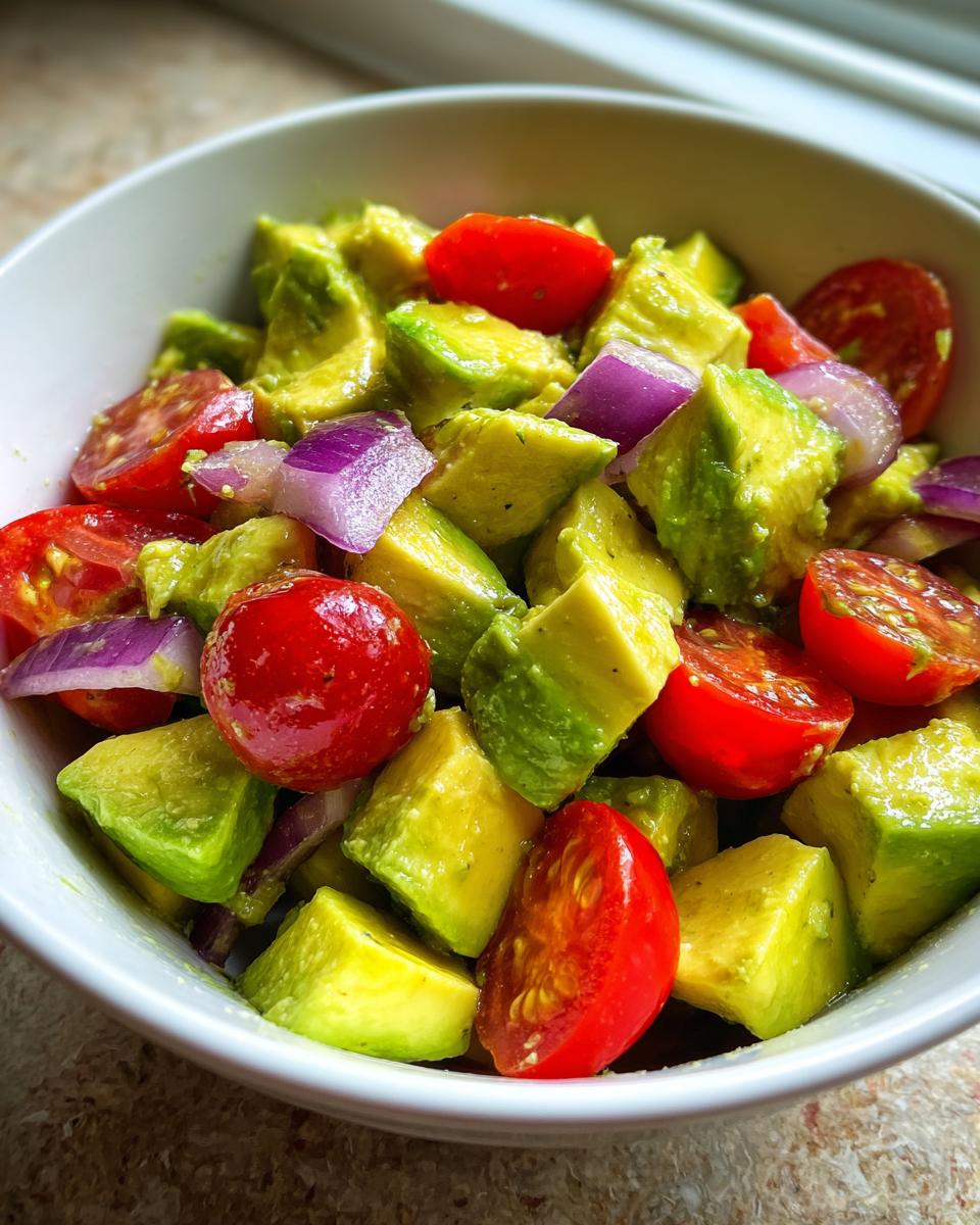 Close-up of diced avocado, cherry tomatoes, and red onion in a white bowl, perfect for Keto Avocado Recipes.