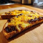 Close-up of toasted bread topped with melted cheese and dark Marmite Recipes spread.