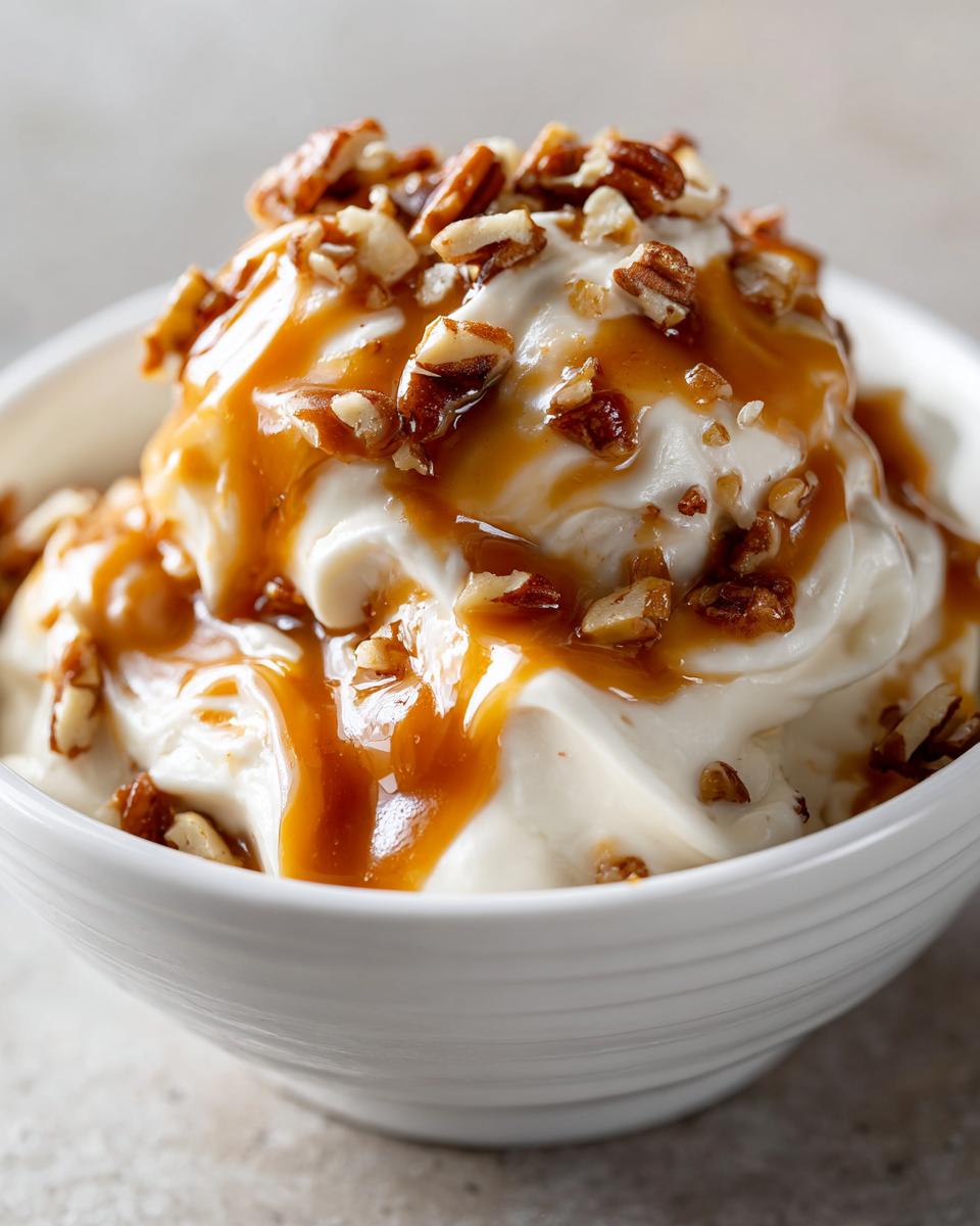 Close-up of a bowl of creamy Caramel Apple Dip drizzled with caramel sauce and chopped pecans.