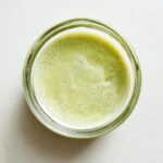Overhead view of a small glass bowl containing a light green, foamy sauce, likely a wasabi recipe.