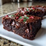 Close-up of a fudgy Christmas Brownies slice topped with red, green, and white sprinkles and visible chocolate chips.