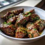 Close-up of tender Garlic Butter Steak Tips coated in a rich, herby garlic butter sauce served in a white bowl.