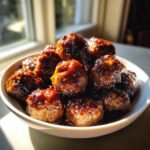 A close-up of glossy, saucy Mongolian Meatballs piled high in a white serving bowl.
