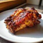 Close-up of two perfectly glazed and caramelized turkey wing pieces on a white plate.