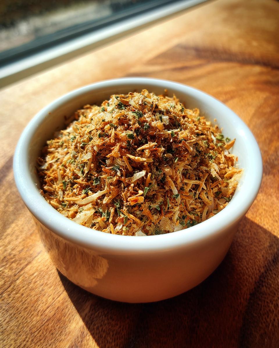 Close-up of homemade Onion Soup Mix, featuring dried onions and herbs, in a small white bowl.
