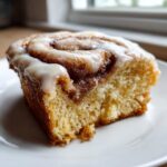 Close-up of a moist slice of Honey Bun Cake with cinnamon swirl and white vanilla glaze.