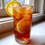 Tall glass of iced tea sweetened with stevia, filled with ice and garnished with lemon slices.
