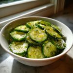 Close-up of marinated, thinly sliced cucumbers in a white bowl, showcasing one of the best Cucumber Recipes.