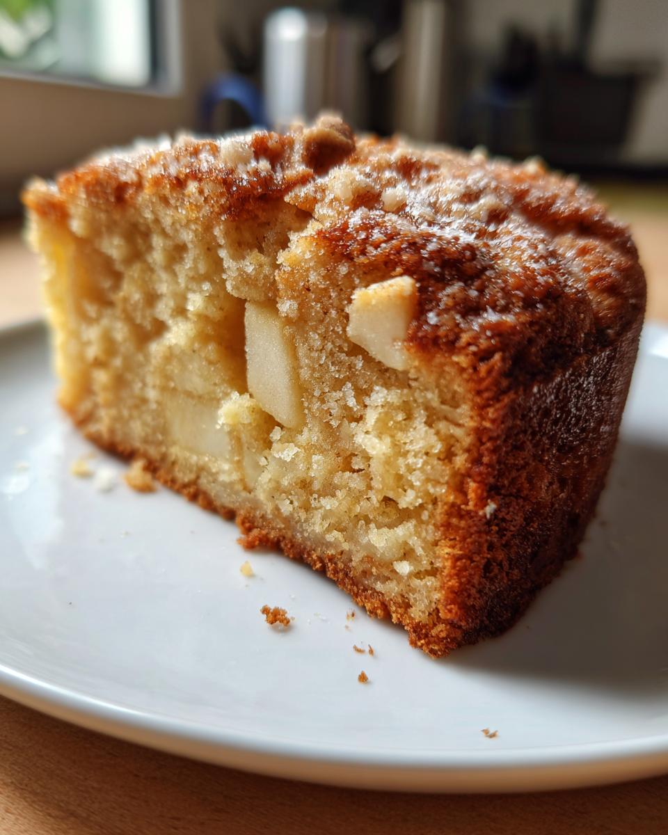 Close-up of a moist slice of Apple Cake Recipes showing chunks of baked apple inside and a sugary crumb topping.